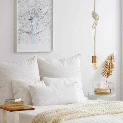 Neatly made bed with white bedding and a framed map on the wall.