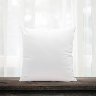 White pillow on a wooden surface with white curtains in the background