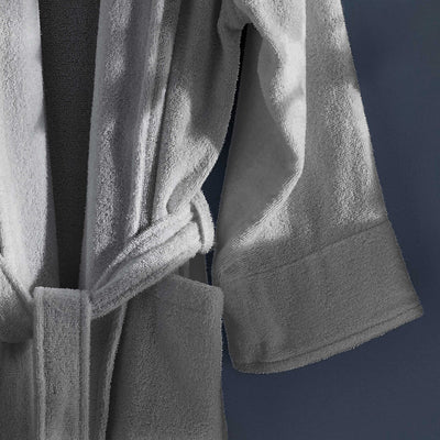 Light gray terry bath robe with a belt and wide sleeves, hanging against a dark background.
