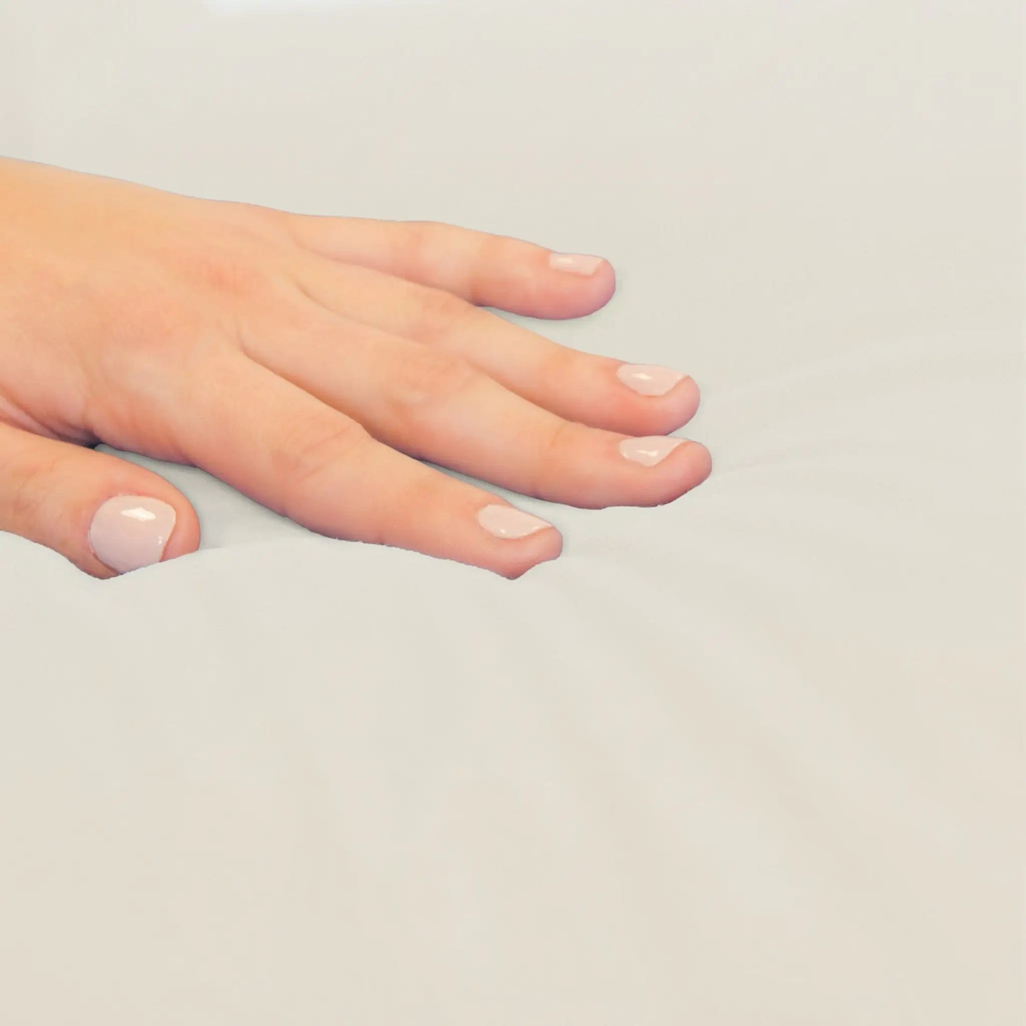 A close-up of a hand with a smooth, resting on a light beige fabric surface.
