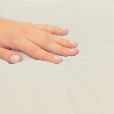 A close-up of a hand with a smooth, resting on a light beige fabric surface.