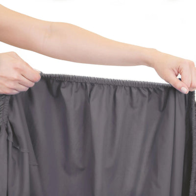 Person holding a gray fitted sheet against a white background