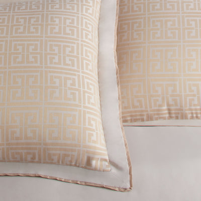 Two decorative pillows with a geometric pattern in soft beige and cream colors, featuring a satin-like finish.