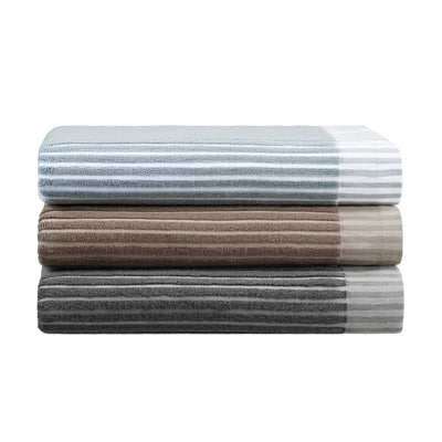 Three stacked towels in varying colors: light blue with stripes, brown, and dark gray.