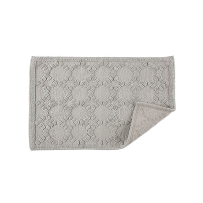 Gray bath rug with a textured circular pattern and a folded corner revealing the backing.