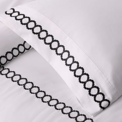 White bedding with black decorative stitching along the edges of the pillowcases.