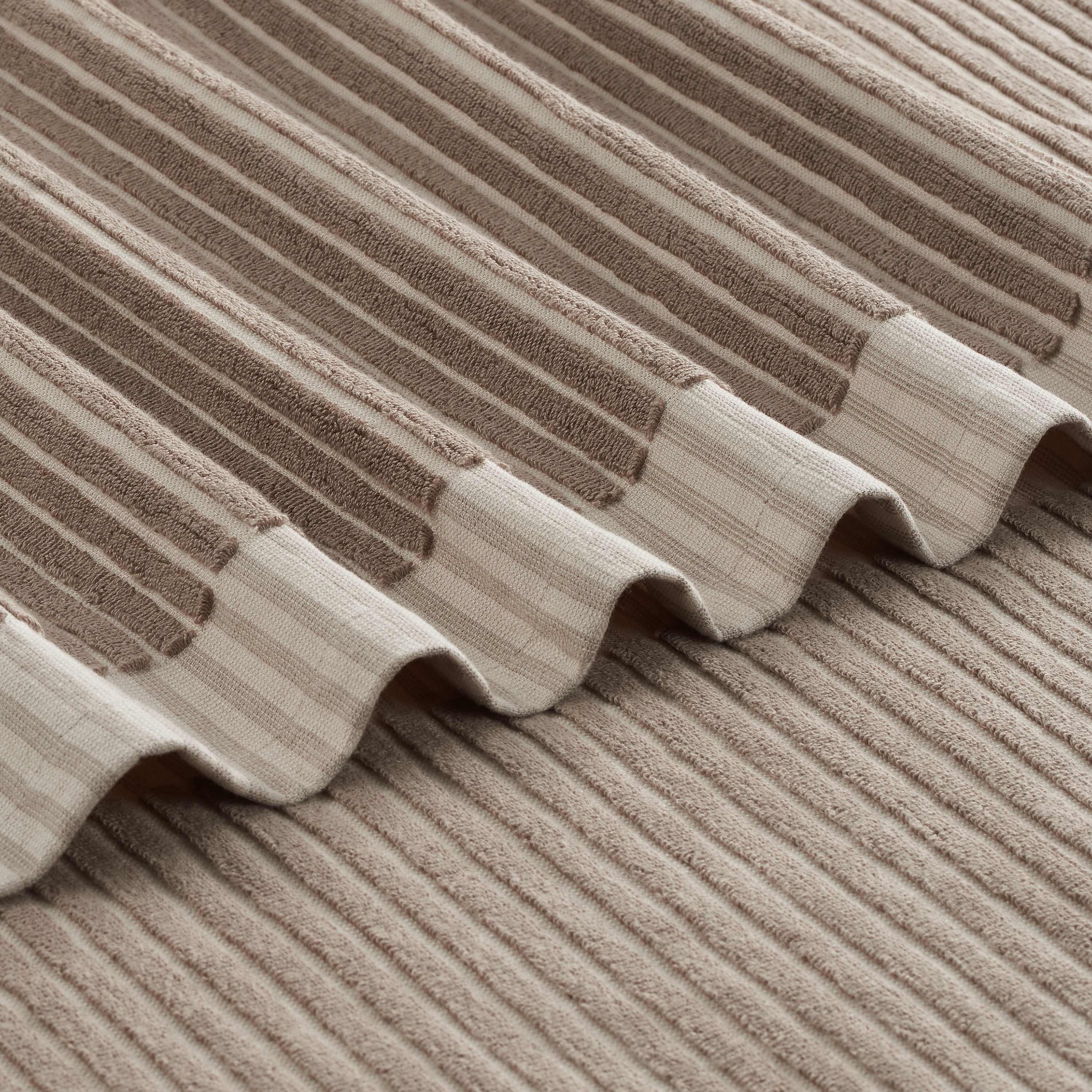 Towel with a sculpted stripe design featuring alternating textured and smooth sections in neutral tones.
