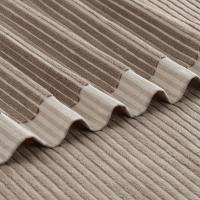 Towel with a sculpted stripe design featuring alternating textured and smooth sections in neutral tones.