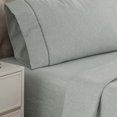 Light green herringbone-patterned sheet set with matching pillowcases on a bed.