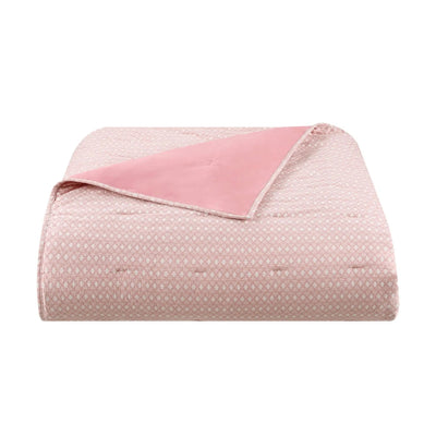 A folded light pink quilt with a subtle repeating geometric pattern and a solid pink reverse side, shown on a plain white background.