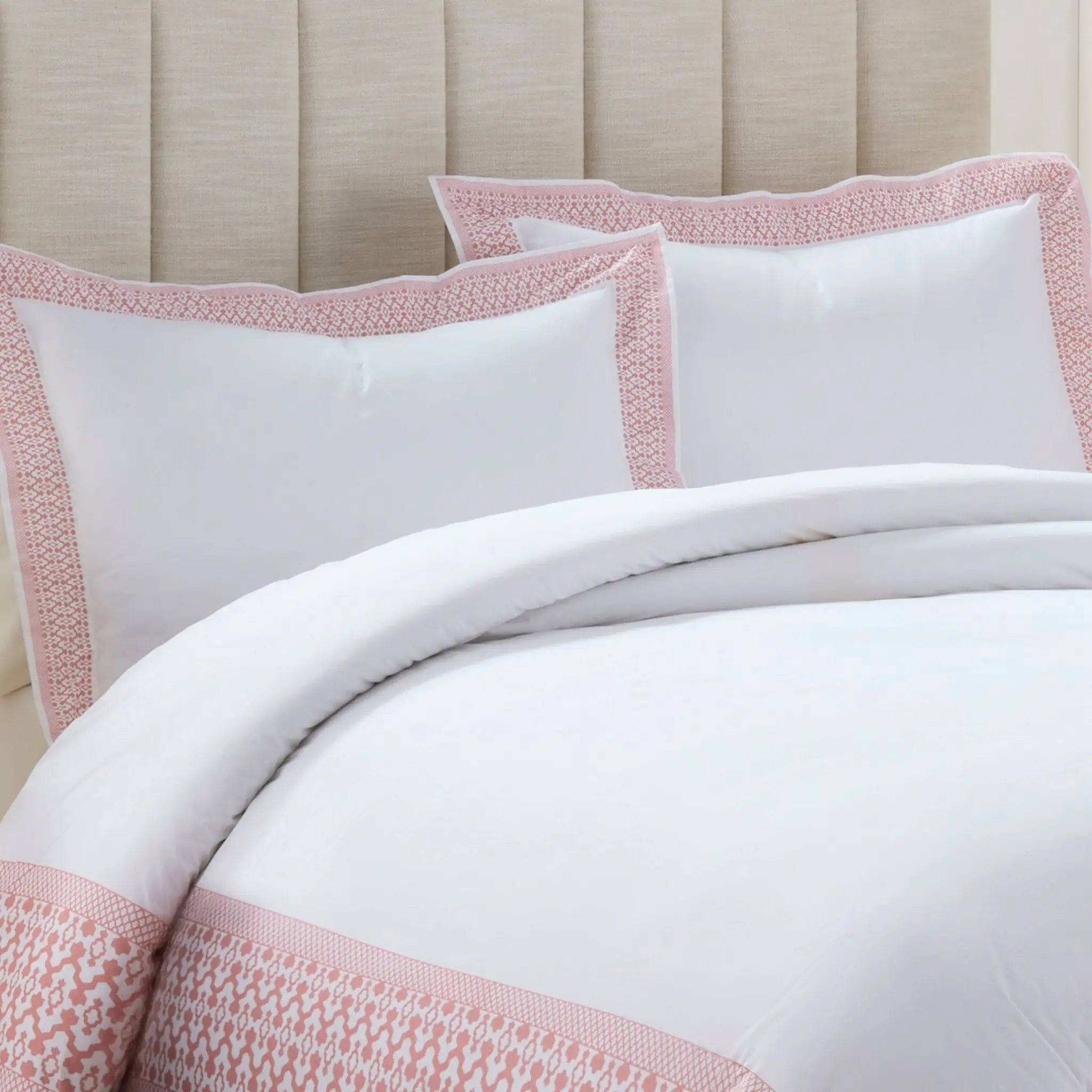White comforter set with pink trim on a bed.