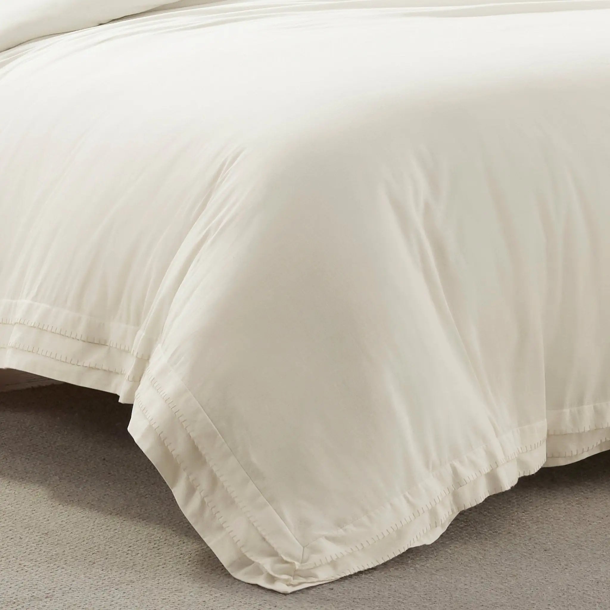 Close-up of an ivory comforter on a bed with a neutral background