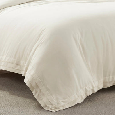 Close-up of an ivory comforter on a bed with a neutral background