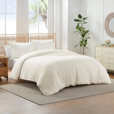 Neatly made bed with ivory comforter set in a bright bedroom