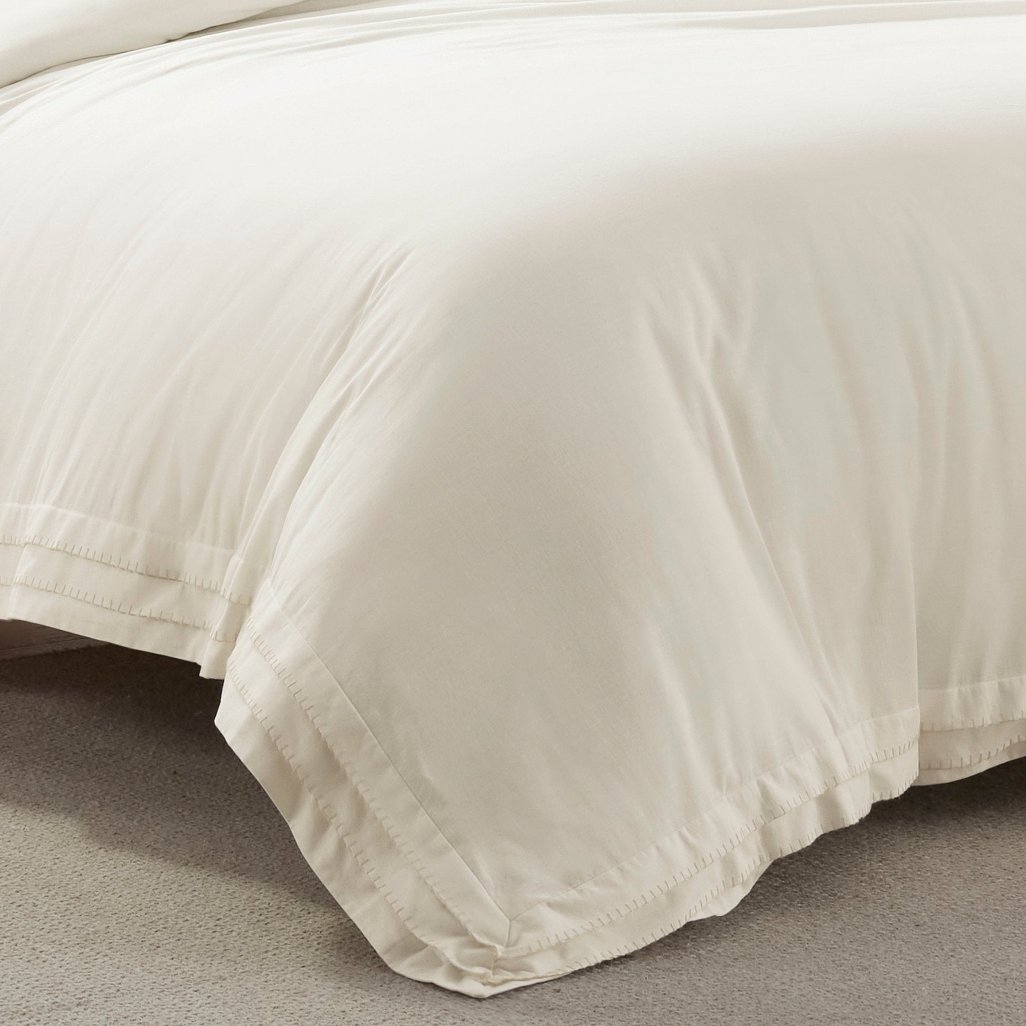 Close-up of a beige comforter on a bed with a neutral background