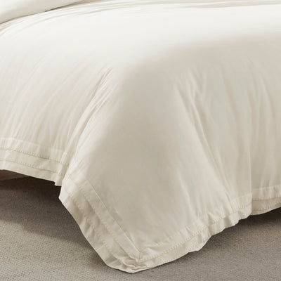 Close-up of a beige comforter on a bed with a neutral background