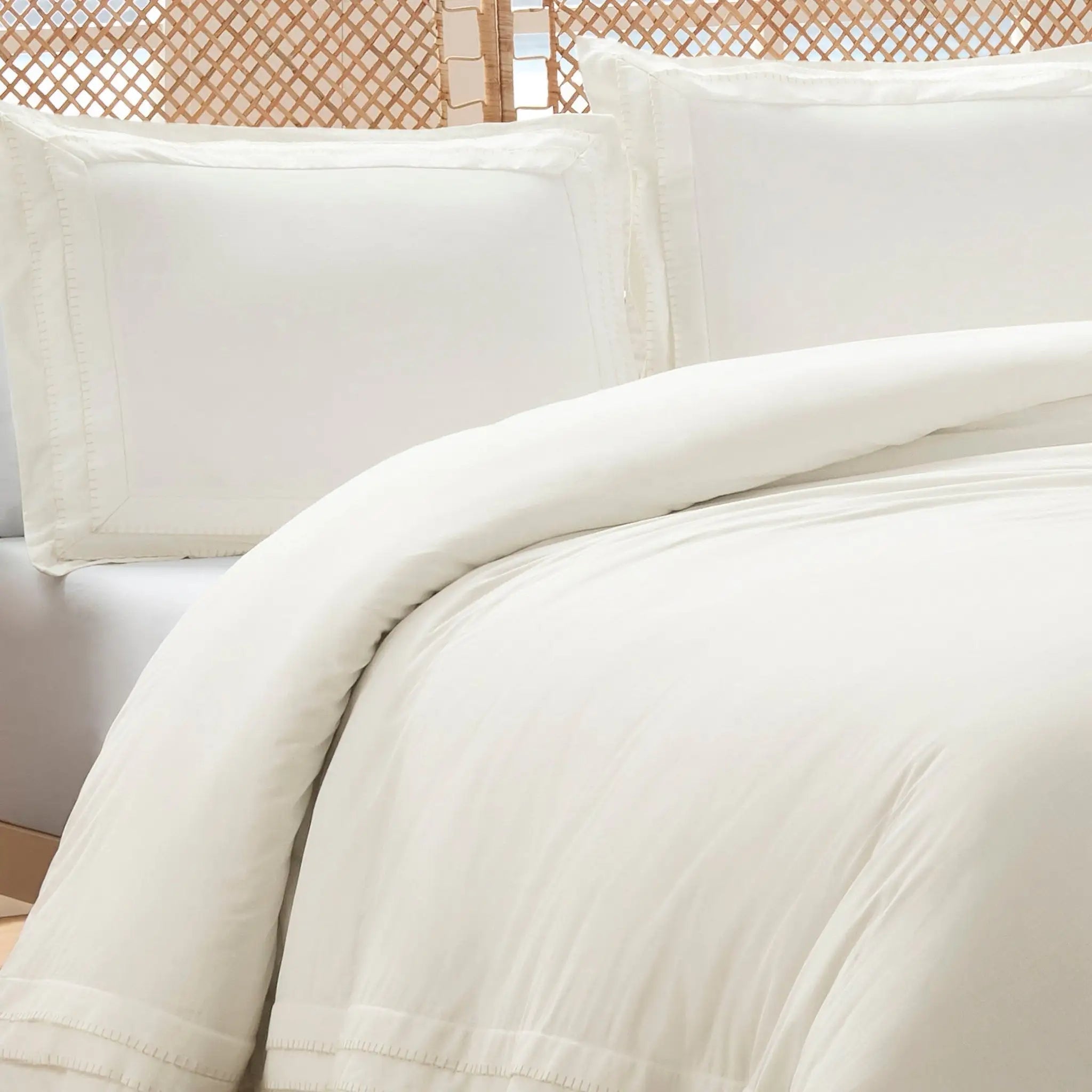 Ivory comforter set, featuring a woven rattan headboard in the background.