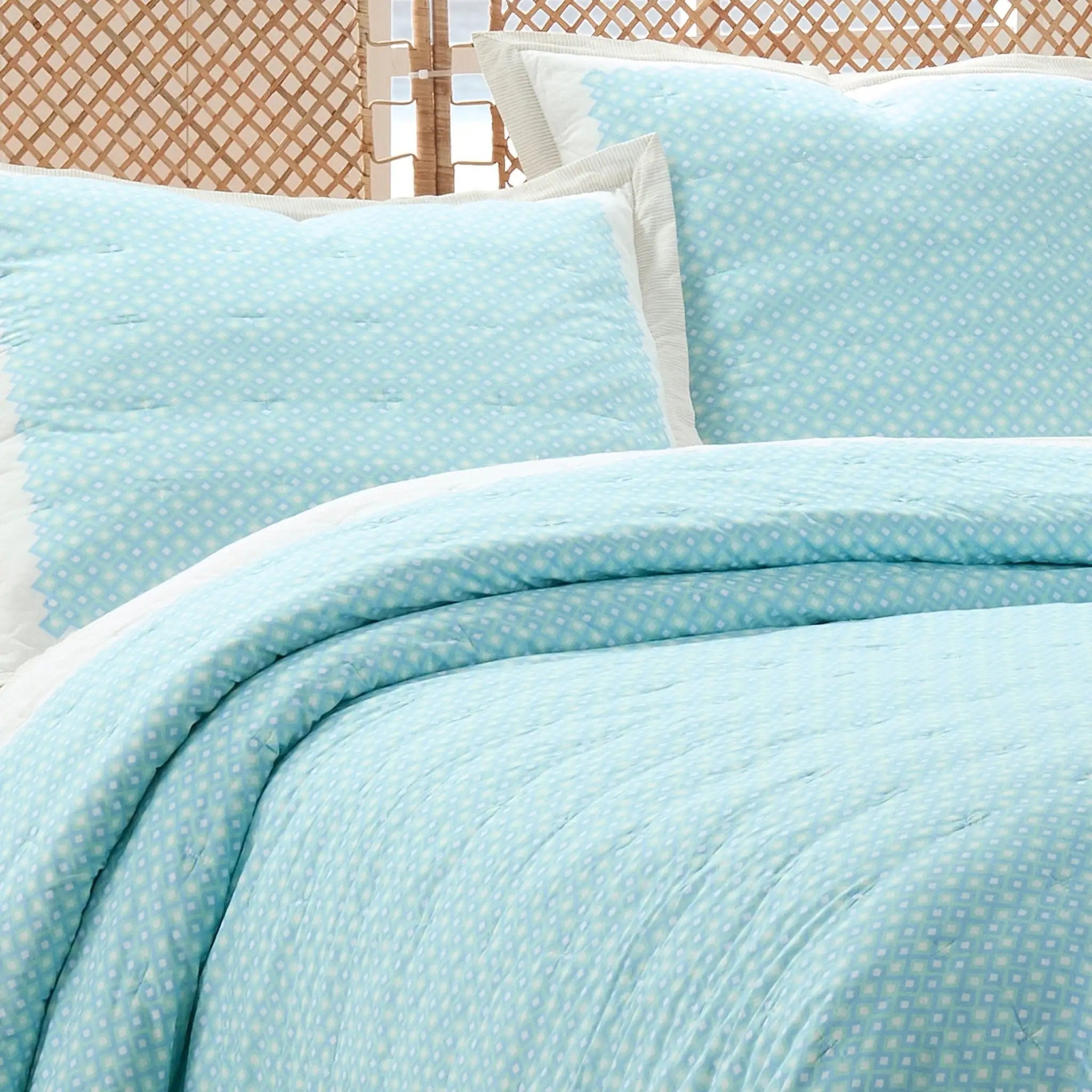 Light blue textured quilt set on a bed with a wooden headboard.