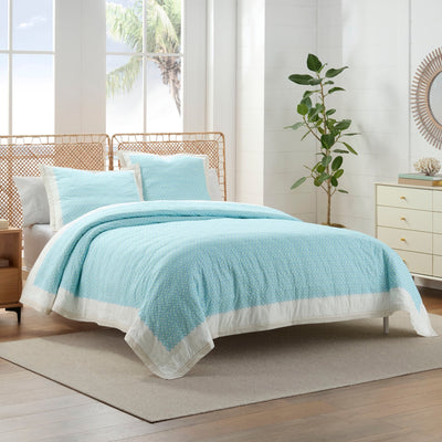 Bedroom with a bed covered in a light blue quilt and euros.