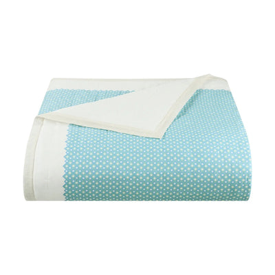 A folded light blue fabric quilt with small white polka dots and a solid white reverse side, shown on a plain white background.