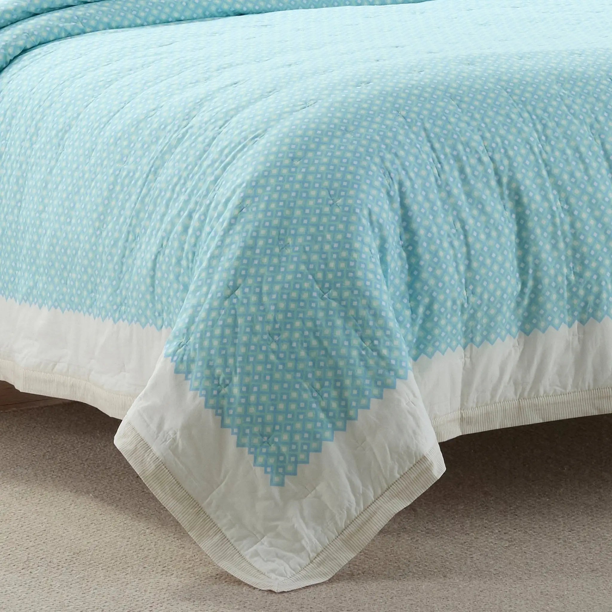 Light blue quilt with white border on a bed