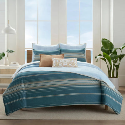 Striped comforter set on a bed in a bright room.