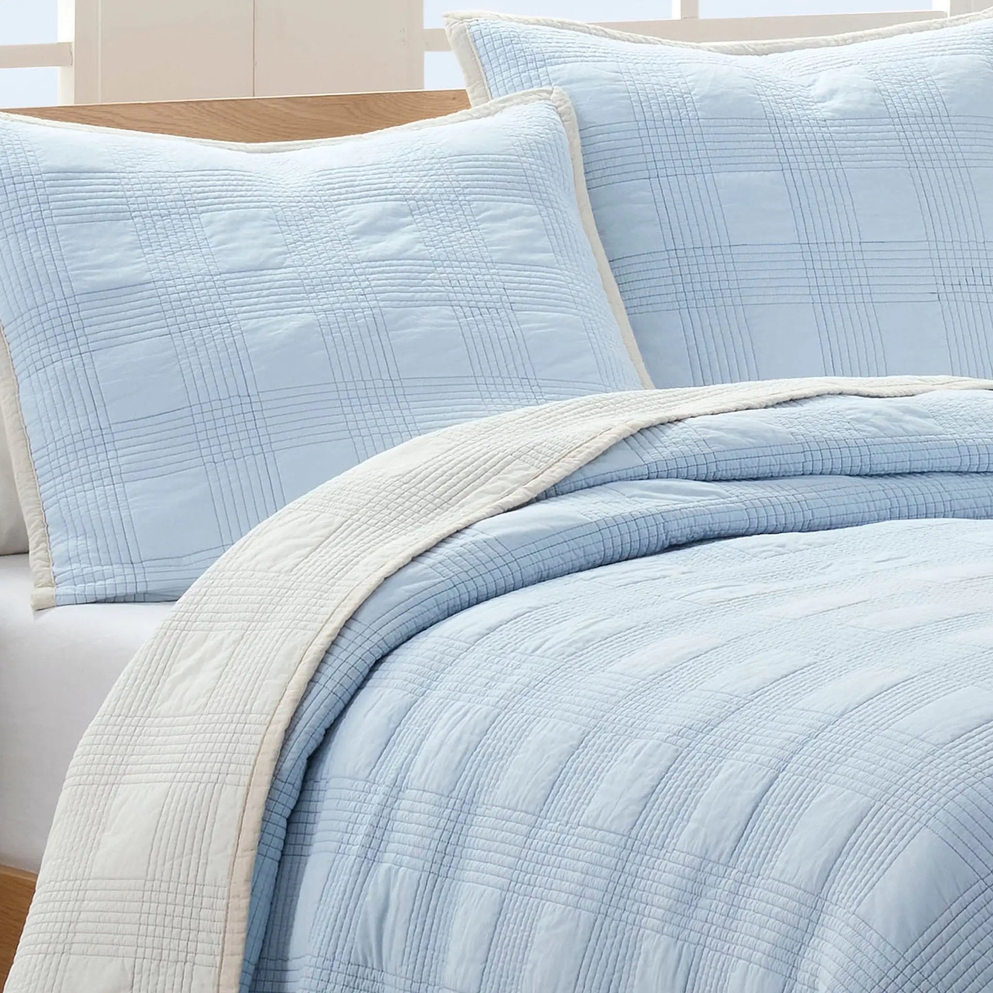 Light blue quilt bedding set with matching euros on a bed.