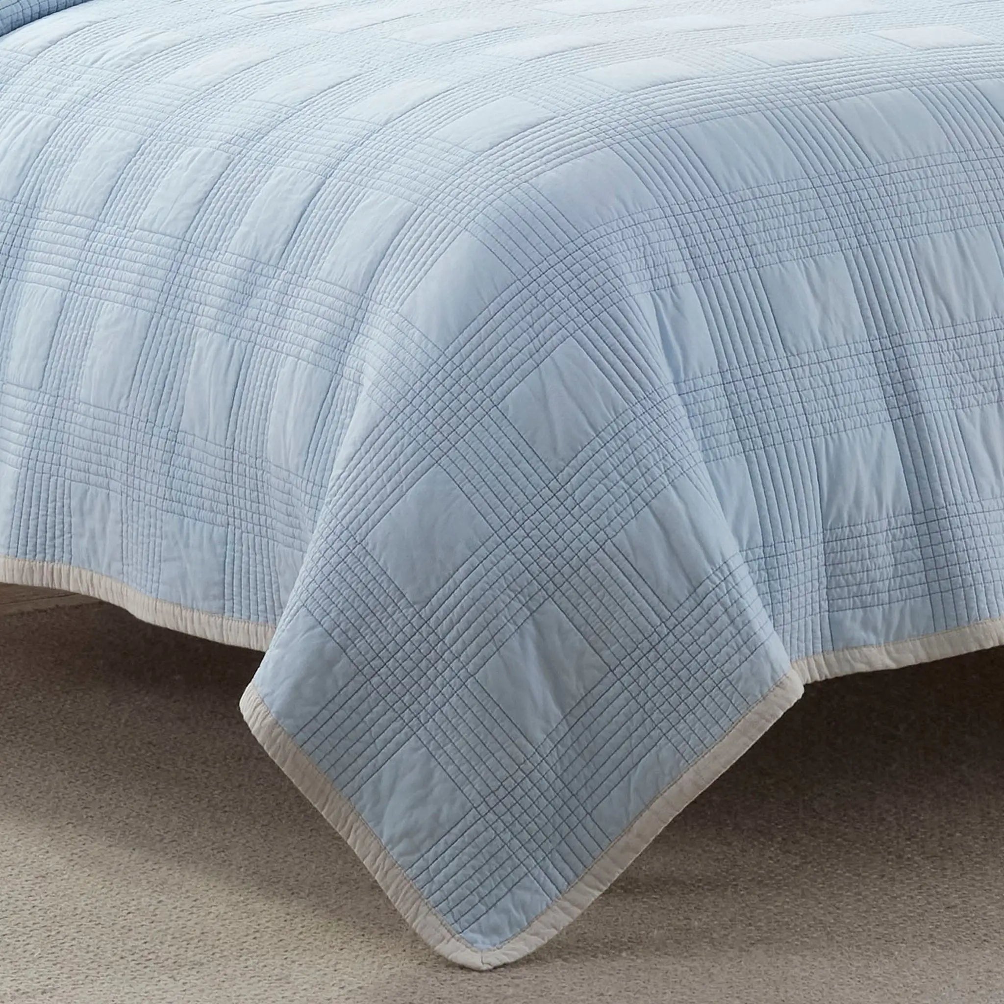 Light blue quilt on a bed with a neutral background