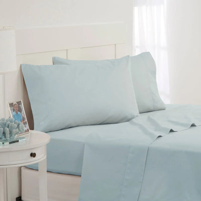 Light blue bed sheet and pillowcase set on a bed in a bright, white bedroom setting.