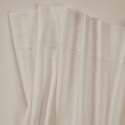 A close-up of draped off-white or cream-colored fabric with soft folds and a smooth texture.
