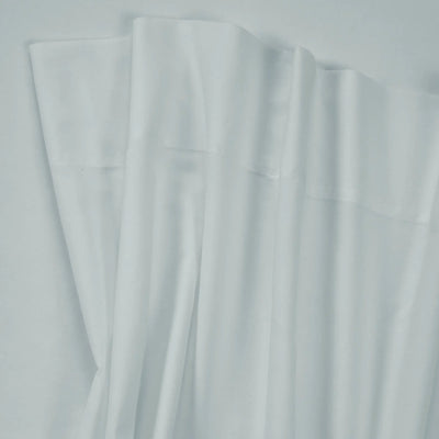 A close-up of white fabric with soft folds and a subtle sheen, filling the frame against a matching light background.