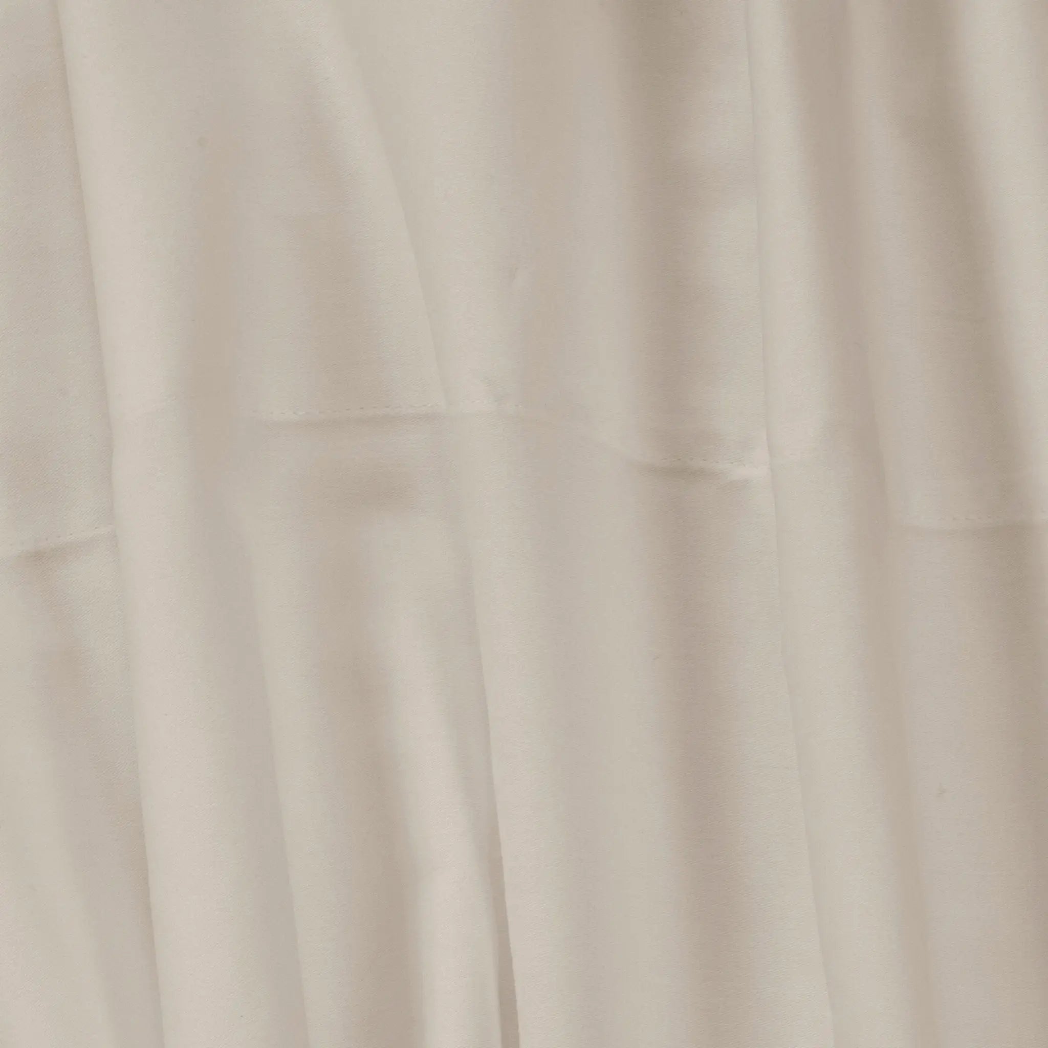 A close-up of draped beige fabric with soft folds and a smooth texture.