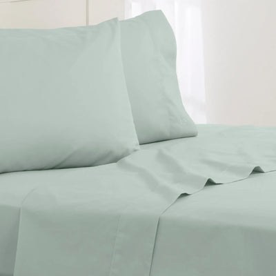 Light green bed sheets and pillowcases on a bed with a white background