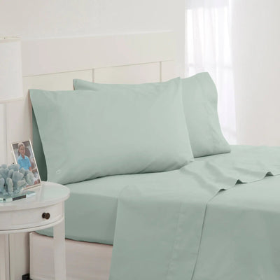 Light green bed sheets and pillowcases on a bed with a white nightstand.