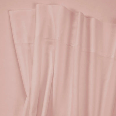 A close-up of draped dusty pink fabric, showing soft folds and a smooth texture.