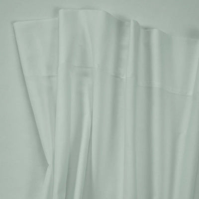 White fabric with a subtle sheen, draped in soft vertical folds against a matching light background.