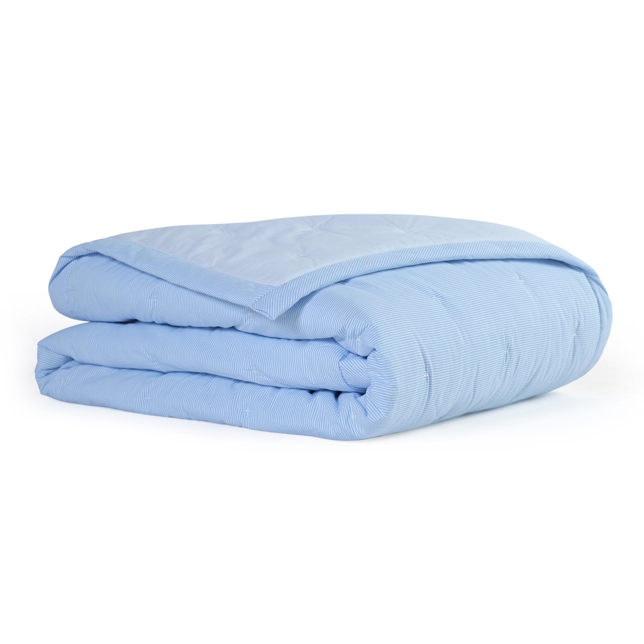 Folded light blue quilt on a white background
