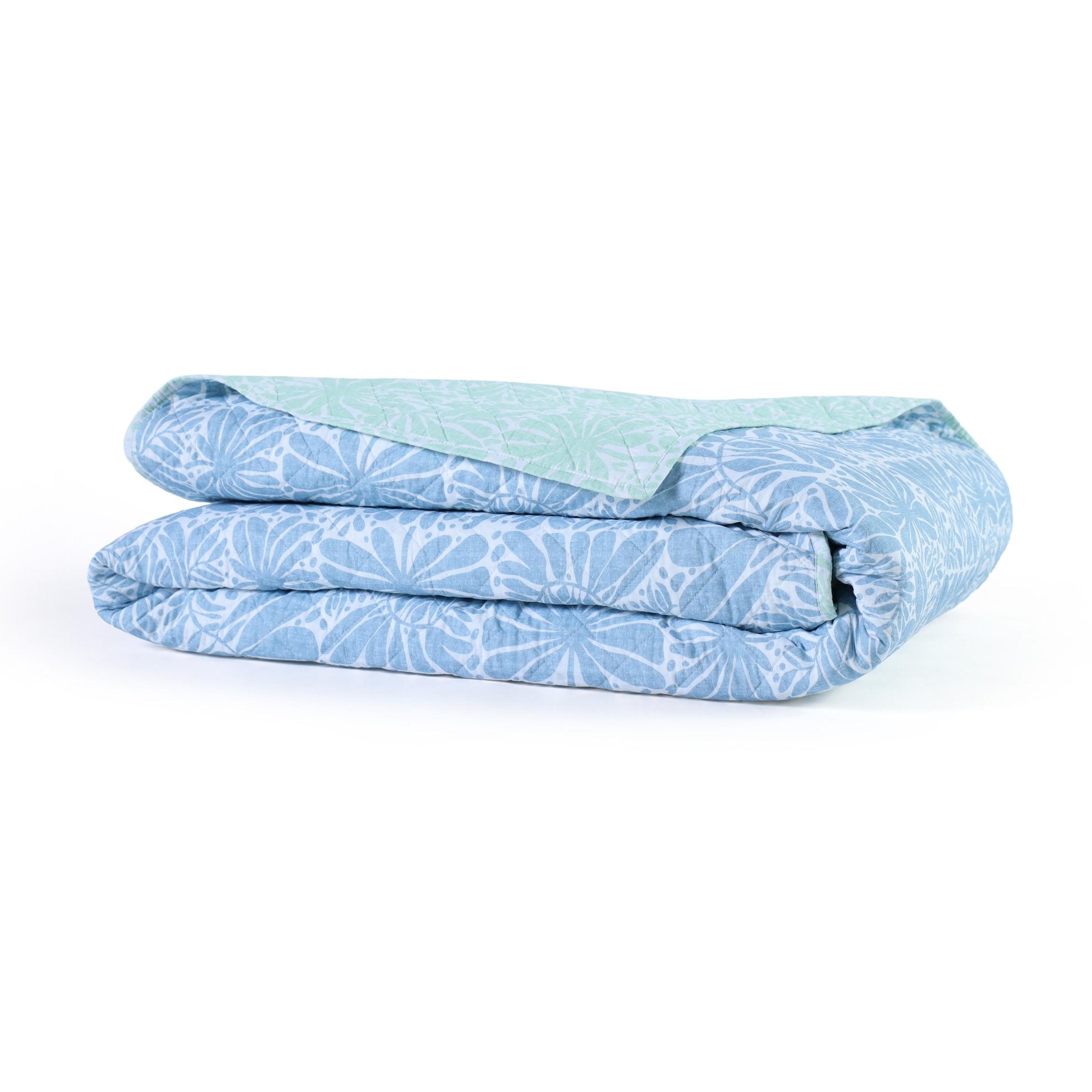 Folded blue and white patterned quilt on a white background