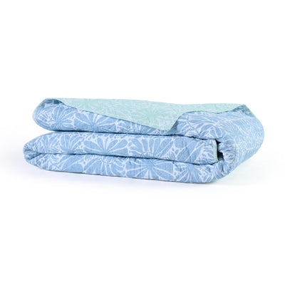 Folded blue and white patterned quilt on a white background