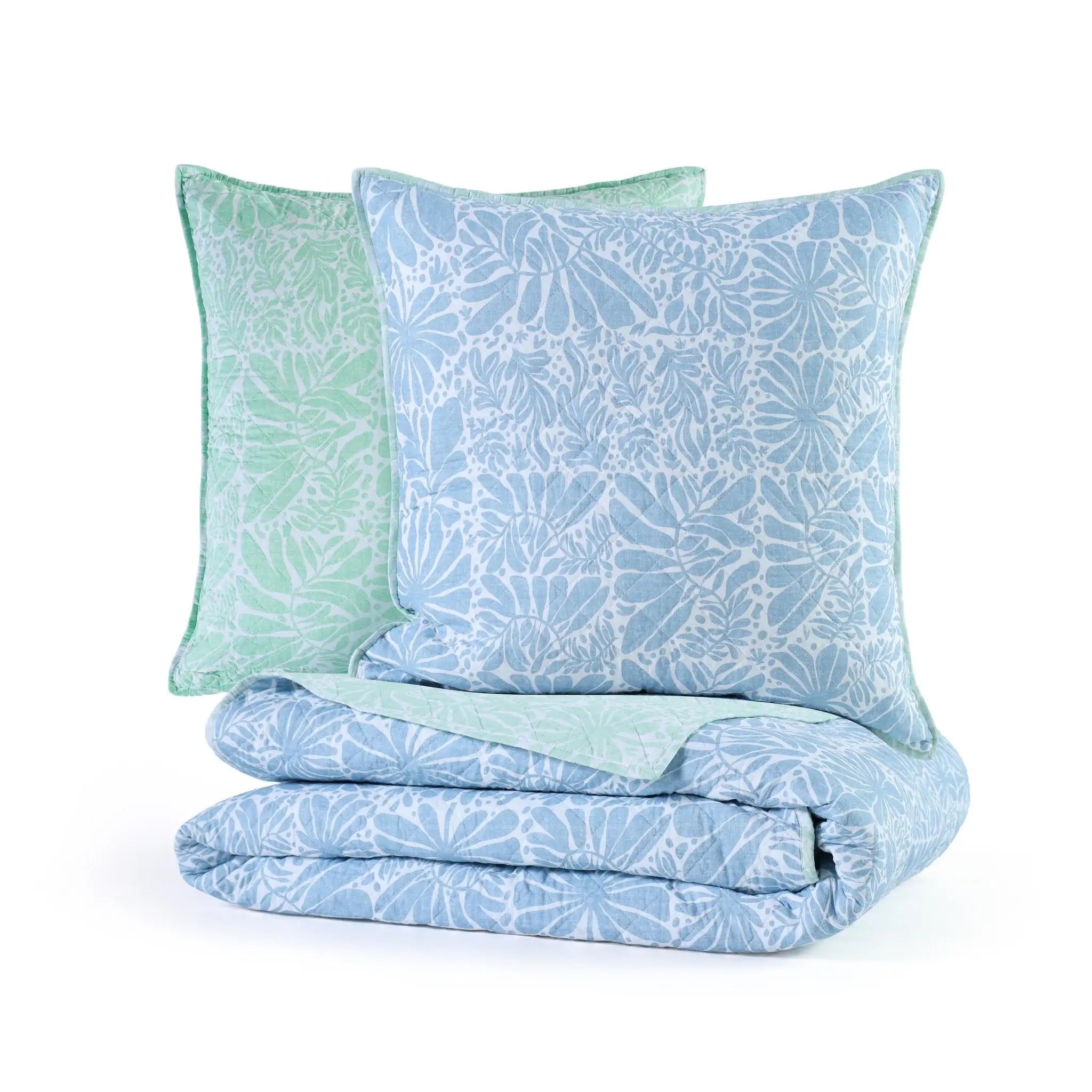 Folded blue and green patterned quilt with matching euros on a white background