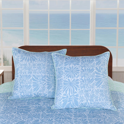 Blue patterned shams on a bed with a window in the background