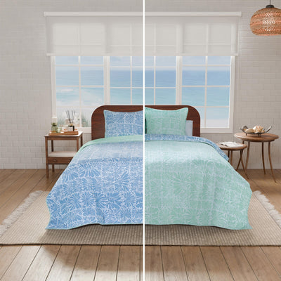 Bedding set with blue and green patterns displayed on a bed in a bedroom setting, showcasing both the front design and the reversible side.
