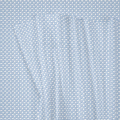 A close-up of a light blue and white fabric with a repeating geometric pattern of interlocking stylized letters or shapes.