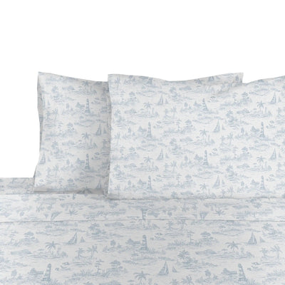 White sheet and pillowcase set with a light blue toile de Jouy pattern featuring palm trees, sailboats, and lighthouses.