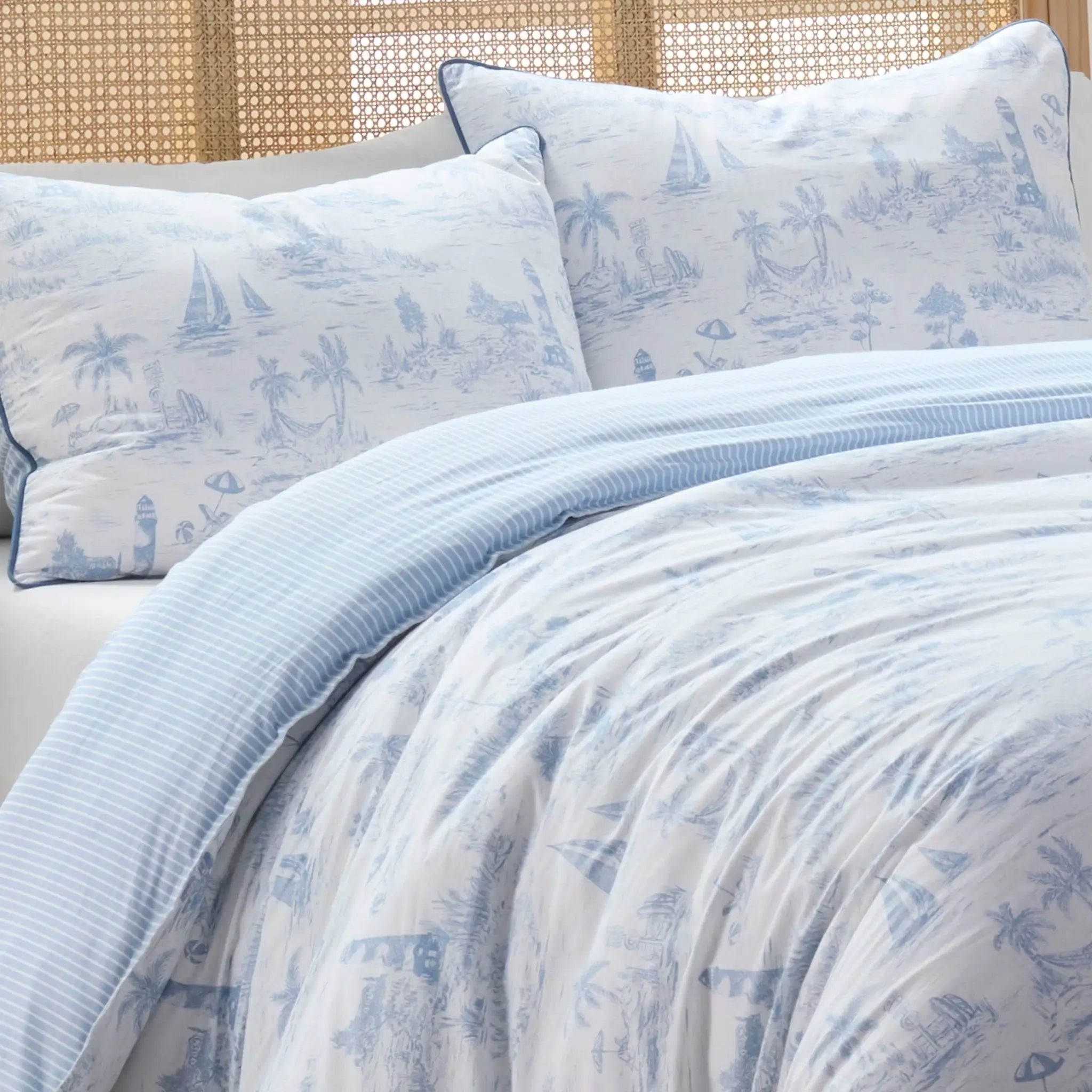 Blue and white patterned comforter set on a bed with a woven headboard.
