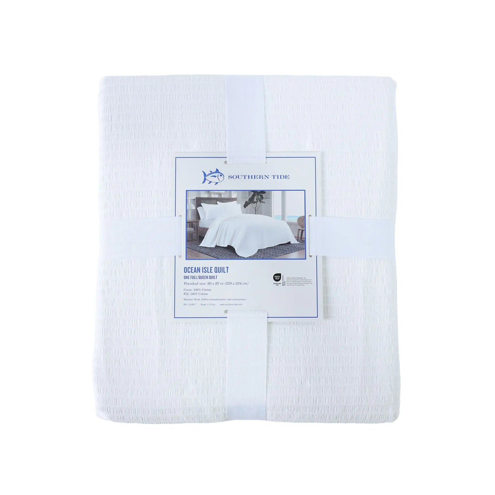 A folded white quilt wrapped with a white band and a paper label that reads Southern Tide Ocean Ile Quilt.