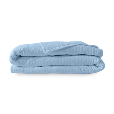 Folded light blue quilt on a white background