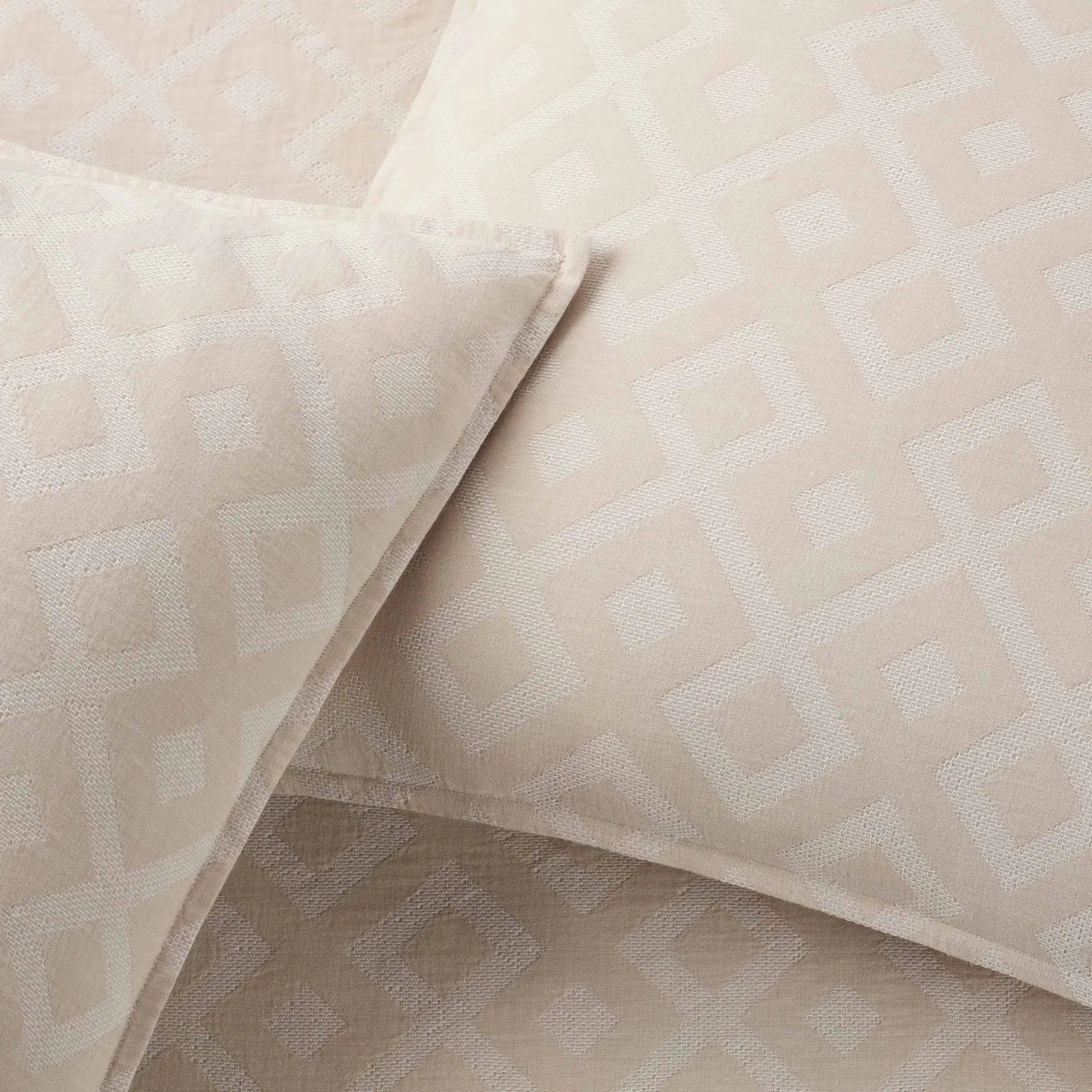 Close-up of beige textured comforter fabric with geometric pattern