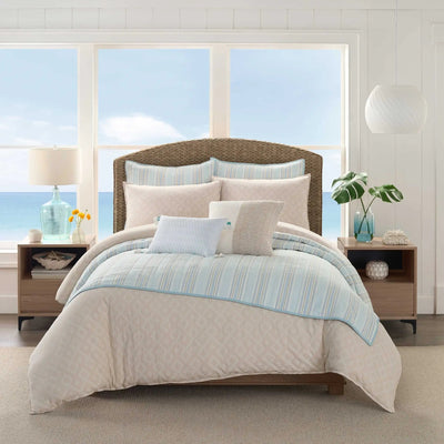 Bedroom with a bed featuring a beige comforter and pillow shams.