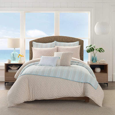 Bedroom with a bed featuring a beige and blue comforter and pillow shams.
